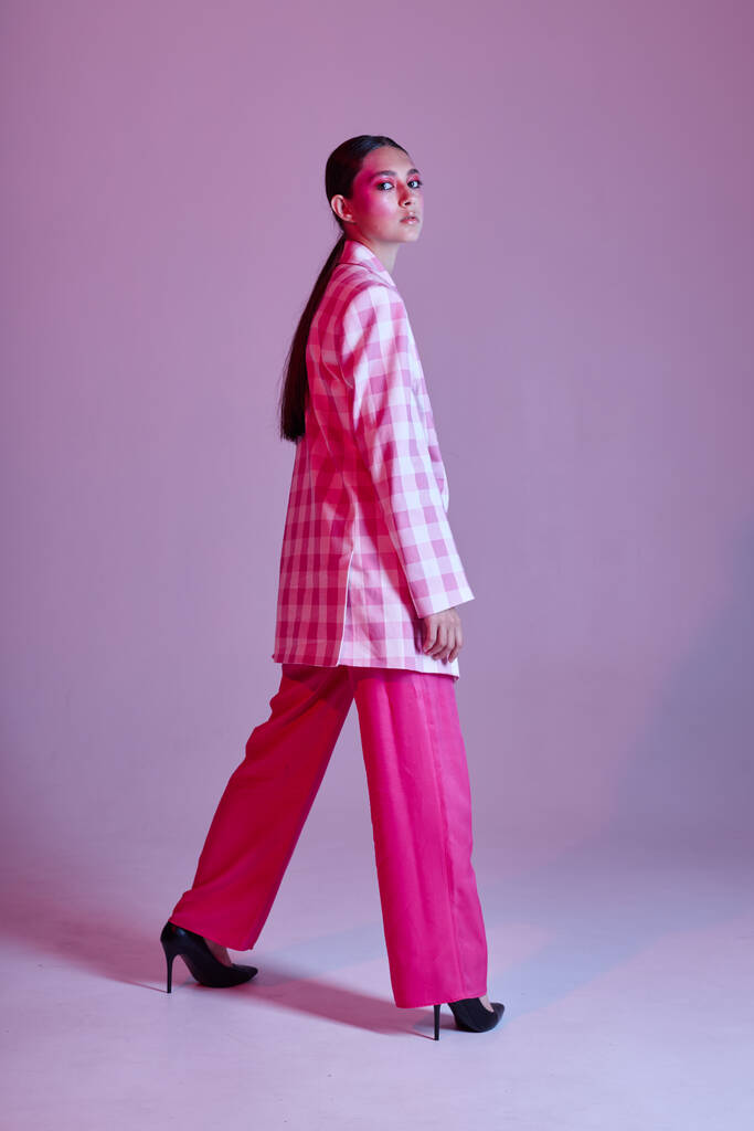 Σέξι μελαχρινή γυναίκα πολυτελή ρούχα μόδα καρό σακάκι ροζ φόντο αναλλοίωτη - Φωτογραφία, εικόνα