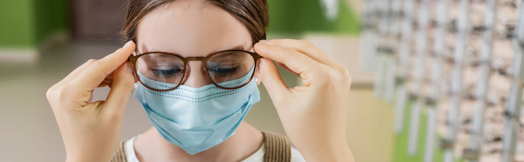 oculist putting eyeglasses on girl in medical mask, banner - Photo, Image