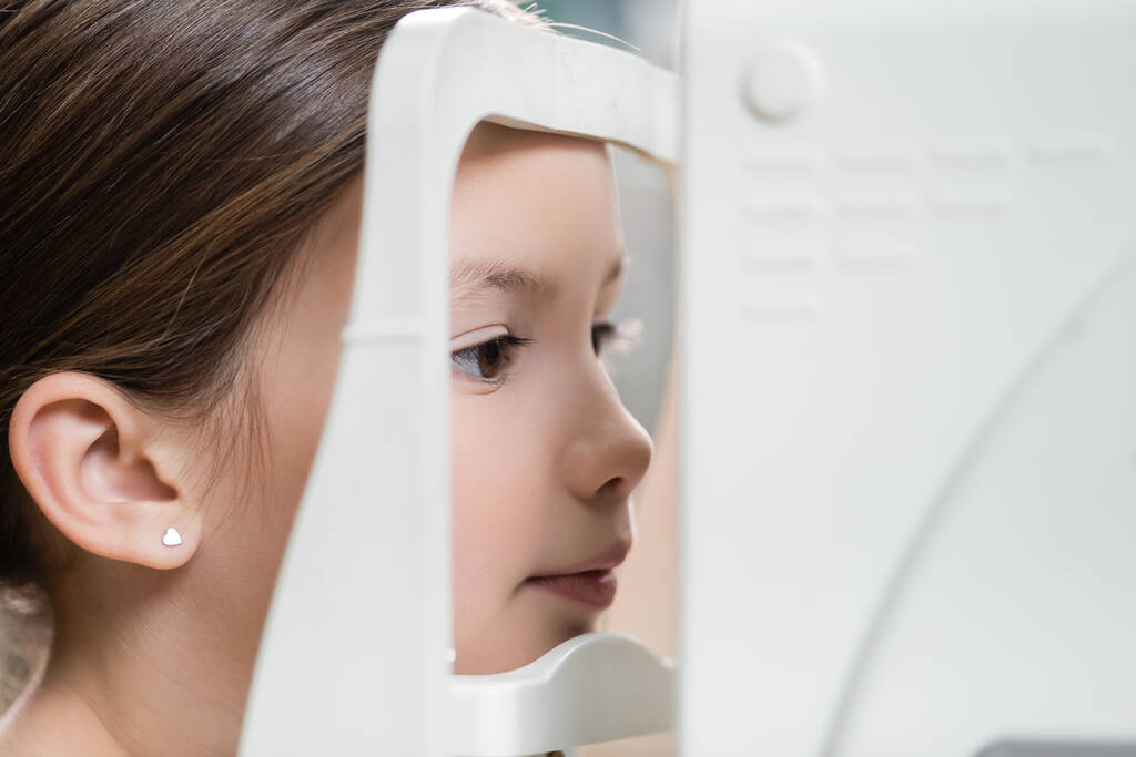girl measuring eyesight on blurred ophthalmoscope  - Fotoğraf, Görsel
