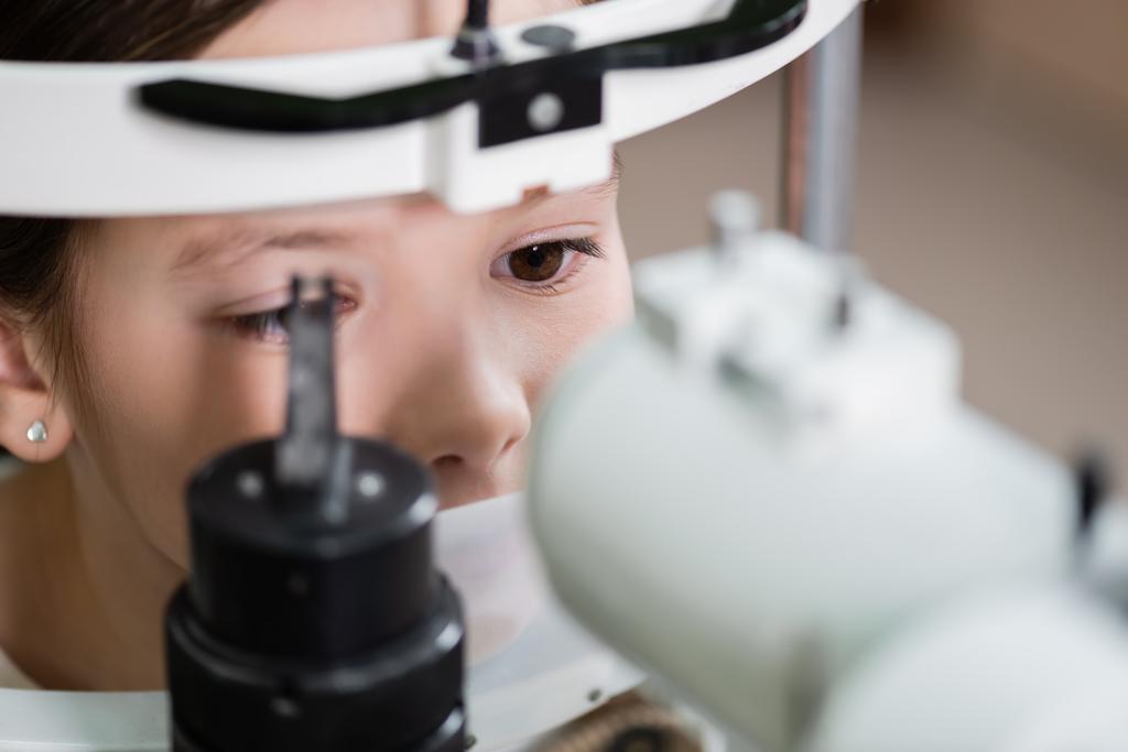 child measuring eyesight on blurred autorefractor - Fotó, kép