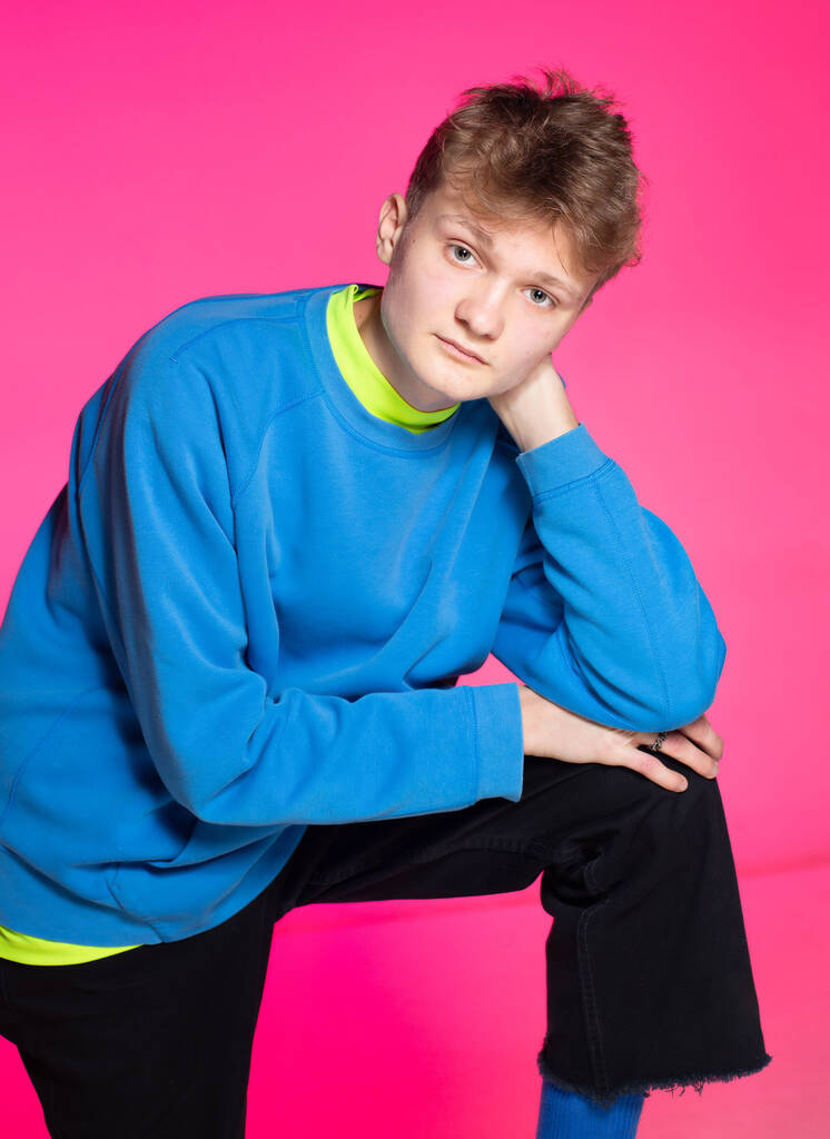 Young european boy with white skin isolated on pink leaning on his knee - Foto, afbeelding