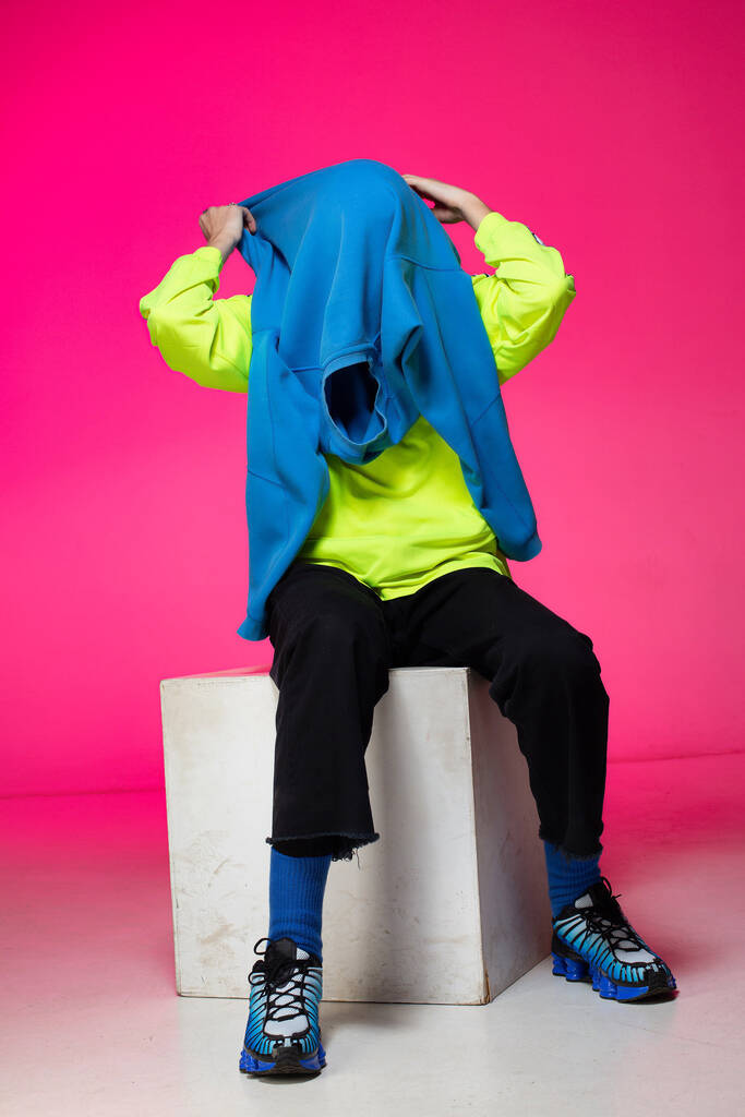 Young european boy with white skin isolated on pink taking off blue hoody - Foto, immagini