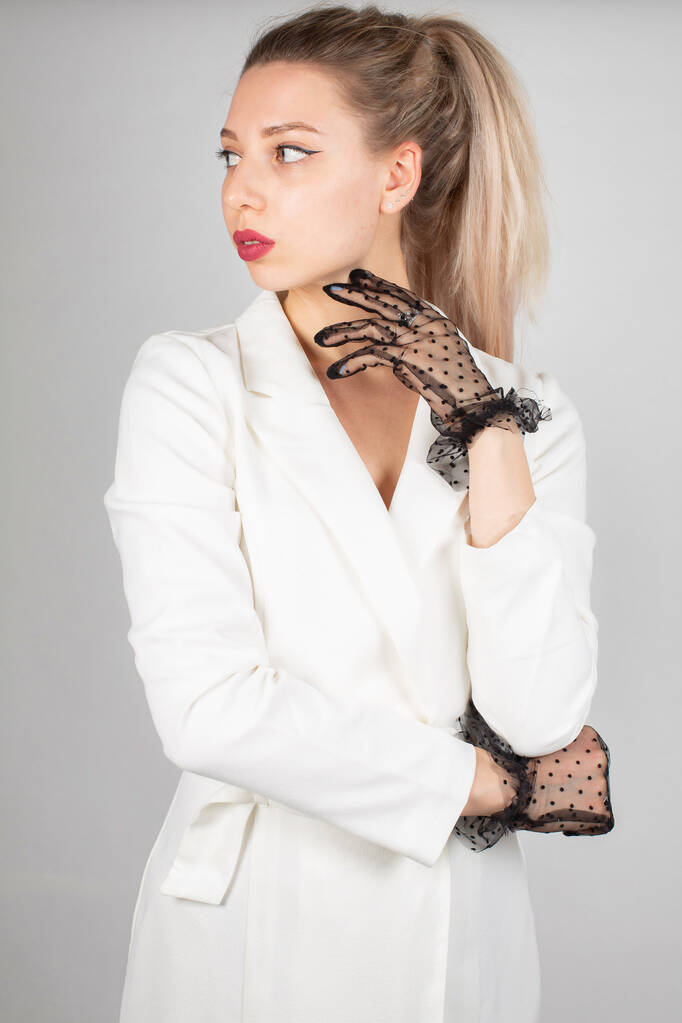 Woman with long hair and white skin isolated on grey in white dress with lace gloves - Foto, afbeelding