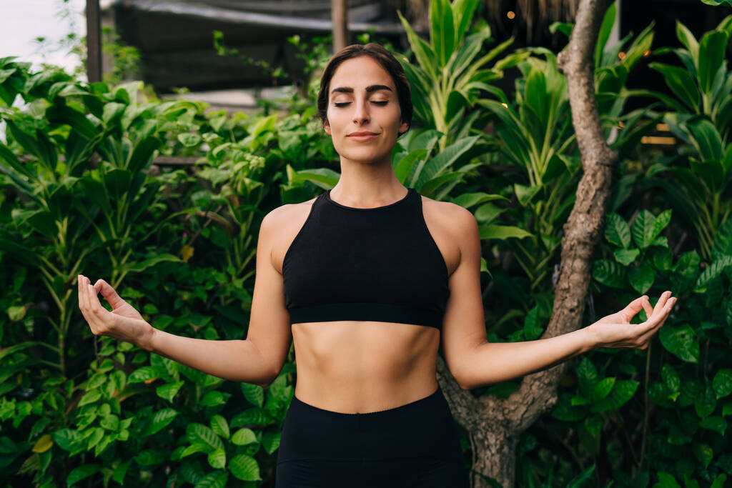 Slim female in sportswear feeling inner peace during morning hatha yoga for getting nature energy, Caucasian woman enjoying pleasure and mindfulness enlightenment during balance concentration - Valokuva, kuva