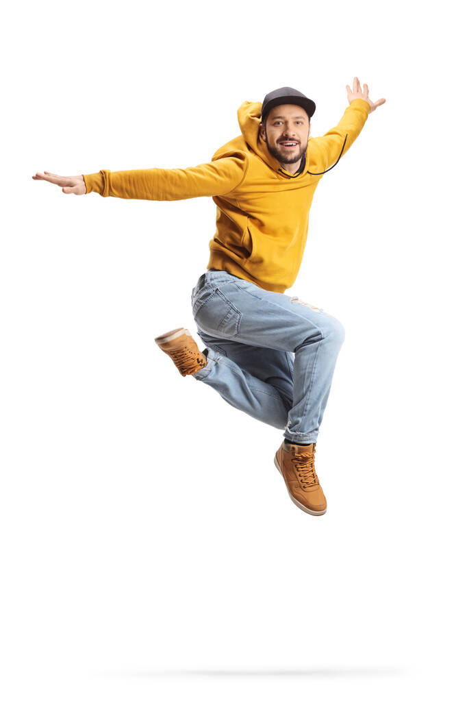 Nuori mies keltaisessa puserossa hyppäämässä ja hymyilemässä eristettynä valkoisella taustalla - Valokuva, kuva