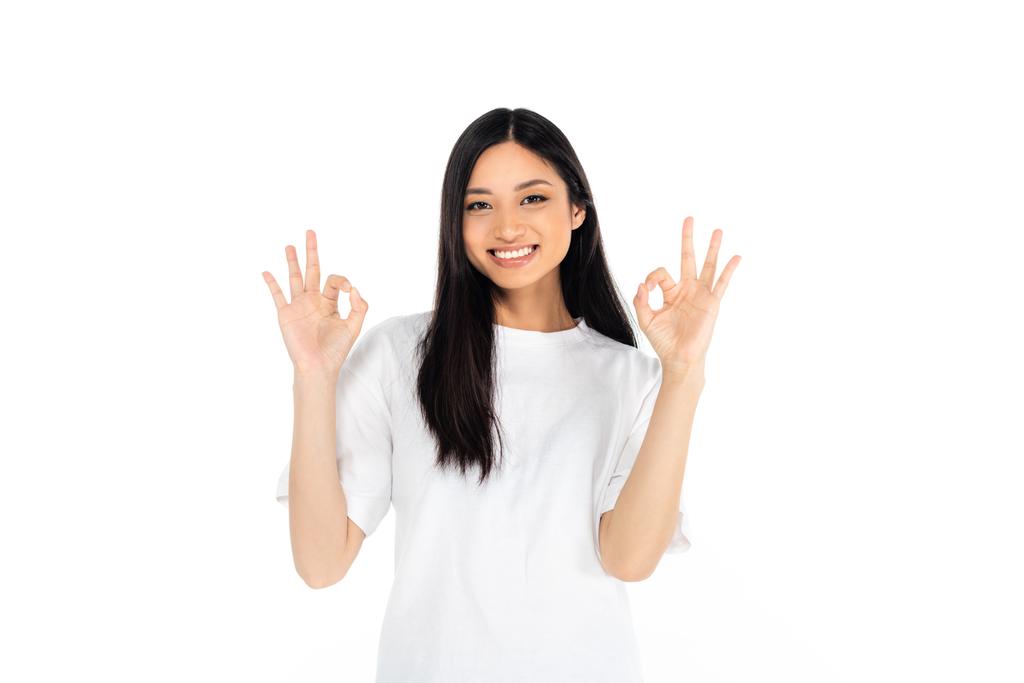Ευτυχισμένη Ασιάτισσα γυναίκα που δείχνει εντάξει σημάδια και κοιτάζει την κάμερα απομονωμένη στα λευκά - Φωτογραφία, εικόνα