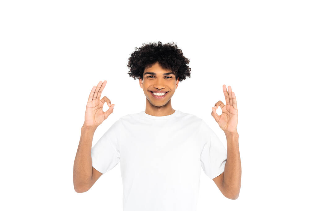 vreugdevolle Afro-Amerikaanse man in t-shirt tonen oke gebaar geïsoleerd op wit - Foto, afbeelding