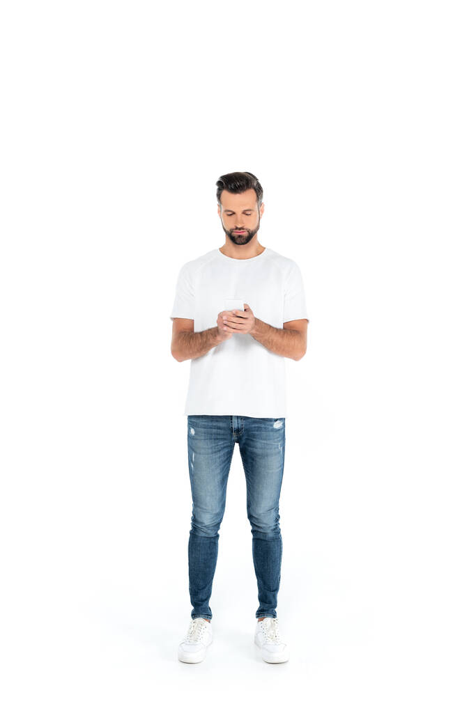 teljes hosszúságú kilátás férfi farmerban csevegés okostelefon fehér - Fotó, kép