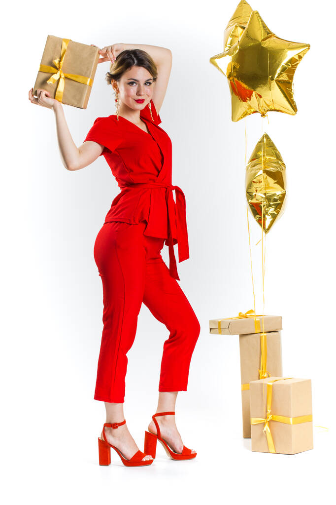 Excited pretty blonde lady in red costume holding stack of gift boxes over white studio background. Celebrating Woman's Day, Valentine's, birthday, anniversary. Shopping for holiday concept - Photo, Image