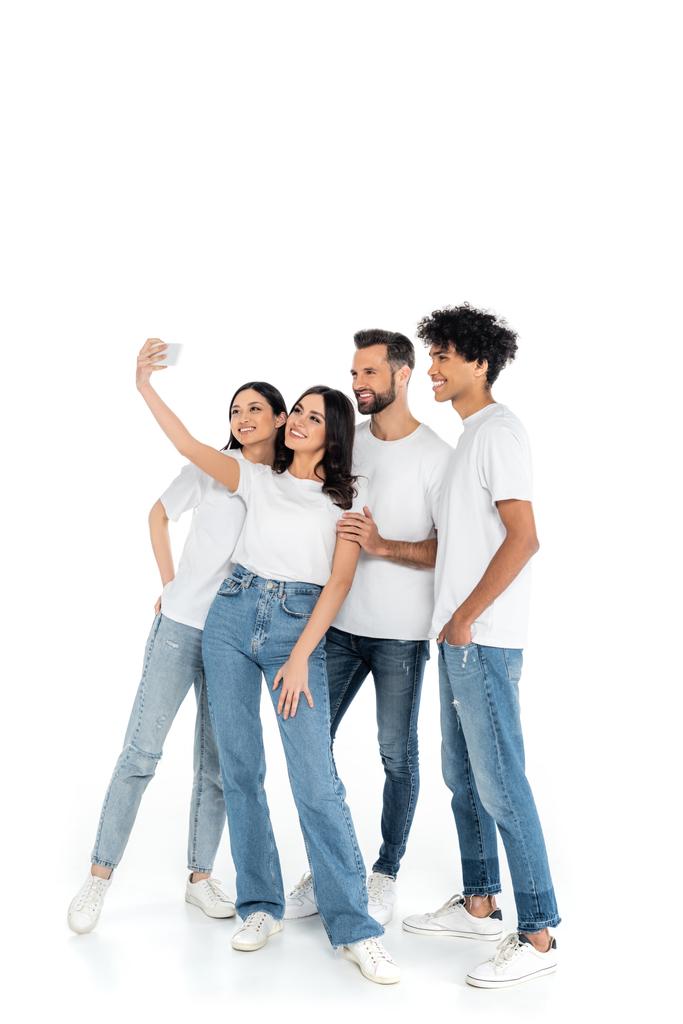 full length view of happy woman taking selfie with multiethnic friends on white - Photo, Image