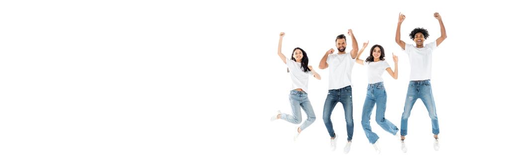 full length view of cheerful interracial friends showing rejoice gesture while levitating isolated on white, banner - Foto, Bild