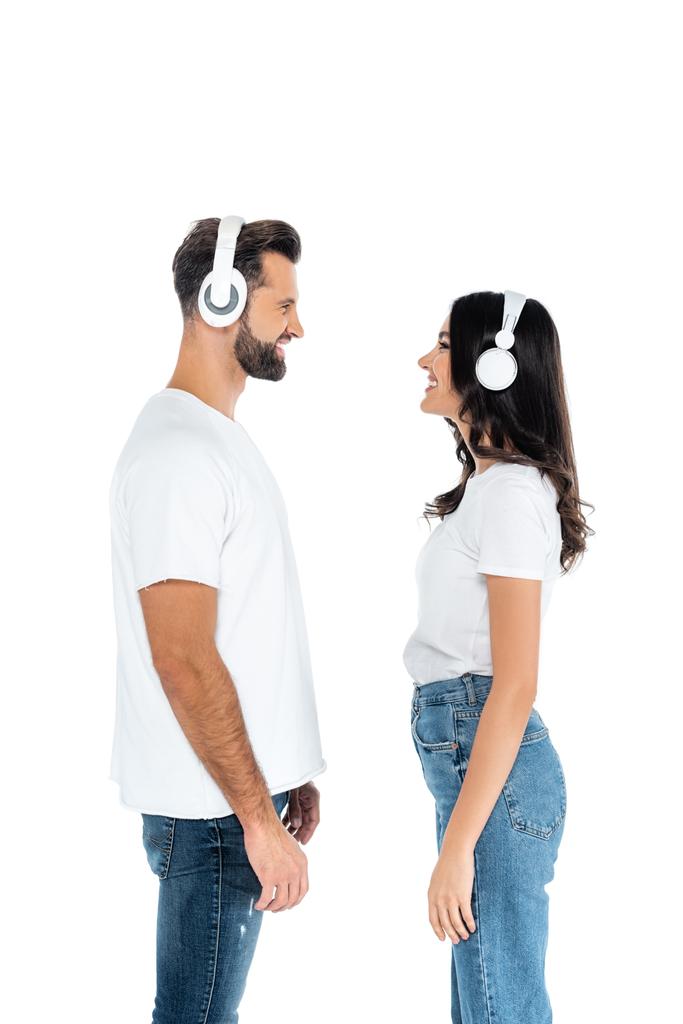 side view of couple in t-shirts and headphones looking at each other isolated on white - 写真・画像