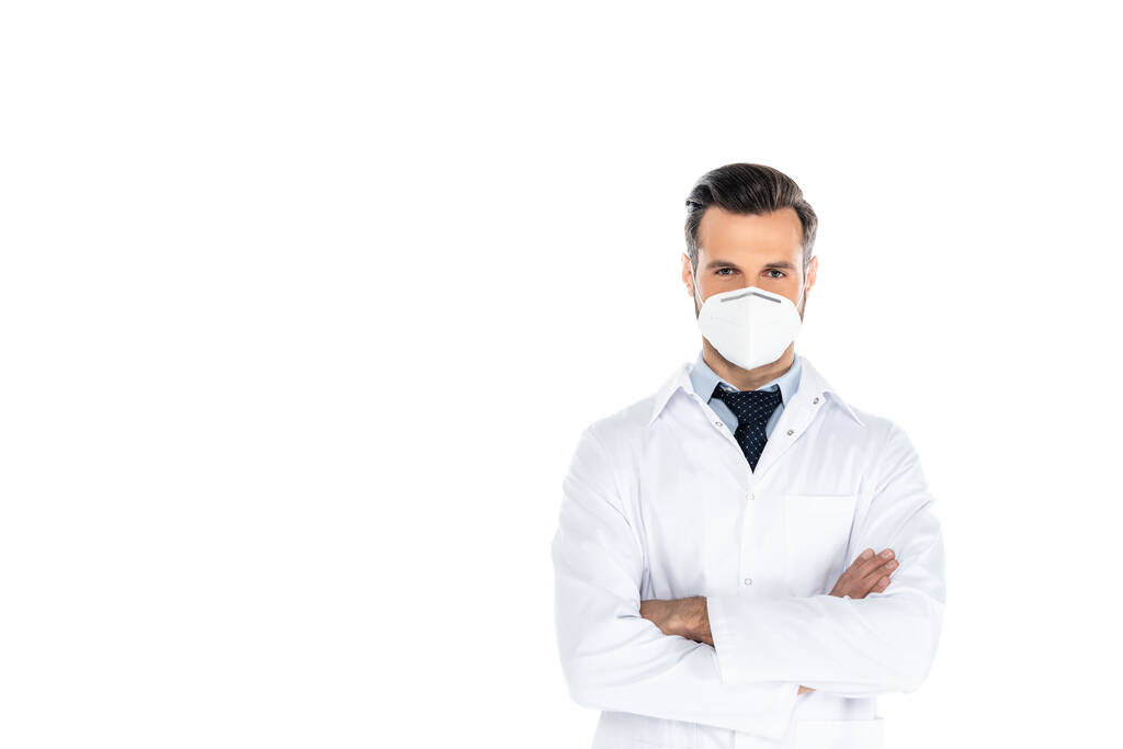 medico in cappotto bianco e maschera medica in piedi con braccia incrociate isolate su bianco - Foto, immagini