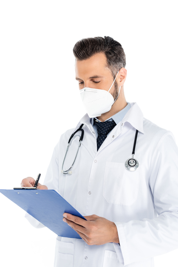 arts met medisch masker en stethoscoop schrijven op klembord geïsoleerd op wit - Foto, afbeelding