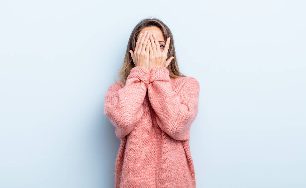 pretty caucasian woman covering face with hands, peeking between fingers with surprised expression and looking to the side - Fotoğraf, Görsel