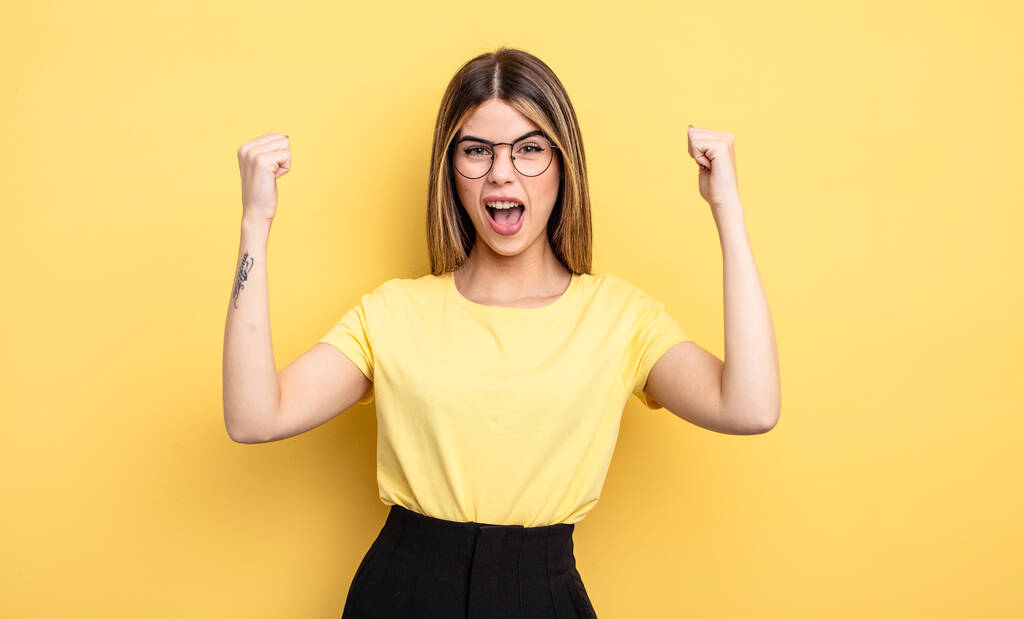 pretty caucasian woman shouting aggressively with an angry expression or with fists clenched celebrating success - Photo, image