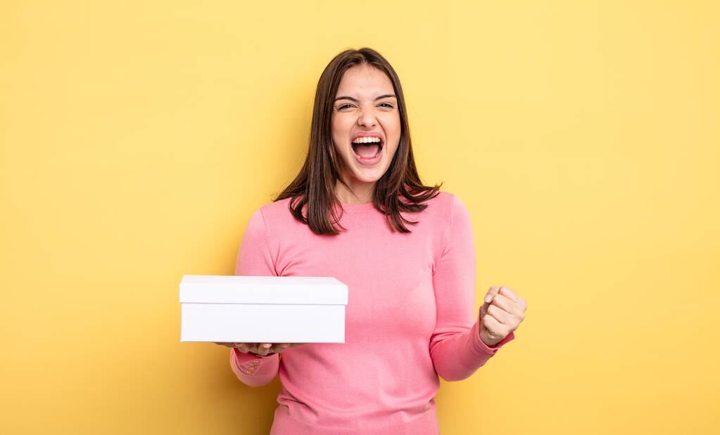 pretty woman shouting aggressively with an angry expression. white box packaging concept - Photo, Image