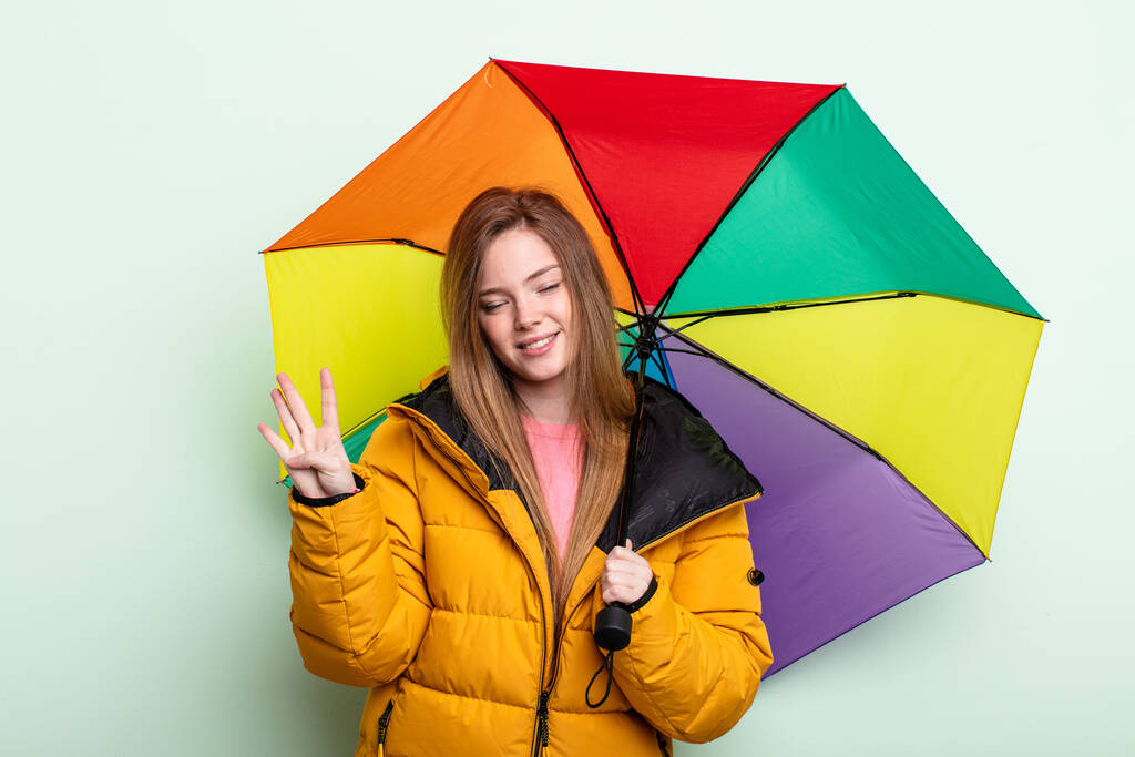 mulher ruiva sorrindo e parecendo amigável, mostrando o número quatro. conceito guarda-chuva - Foto, Imagem