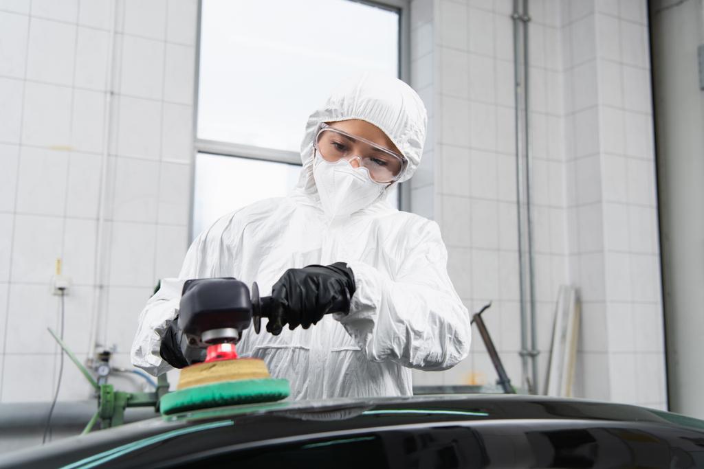 Workwoman in hazmat suit and protective mask polishing car in service  - Zdjęcie, obraz