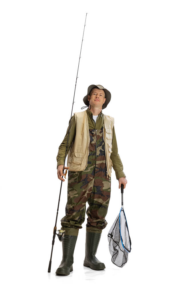 Portrait de jeune homme, pêcheur professionnel avec canne à pêche, filature et équipement allant à la rivière isolé sur fond de studio blanc - Photo, image