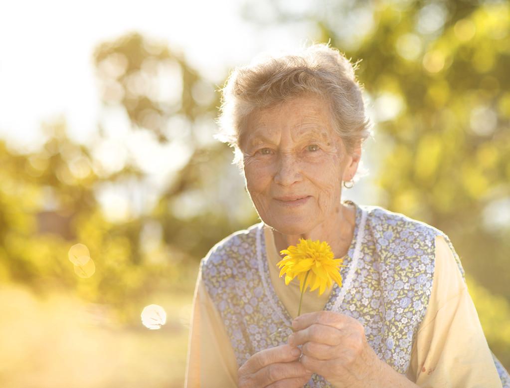 Mujer mayor en delantal con flor
 - Foto, Imagen