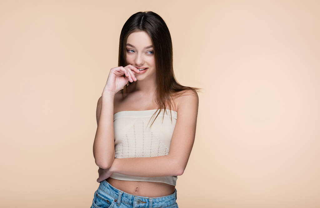 pretty young woman in crop top with bare shoulders smiling isolated on beige - Photo, Image