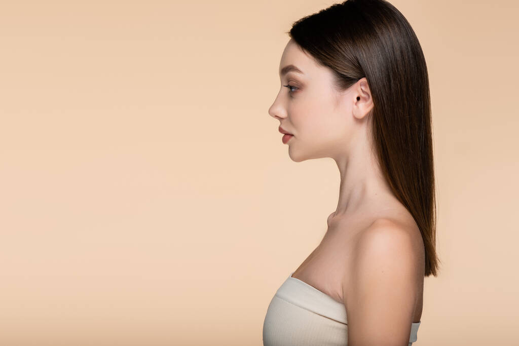side view of young woman in crop top with bare shoulders isolated on beige  - Photo, Image