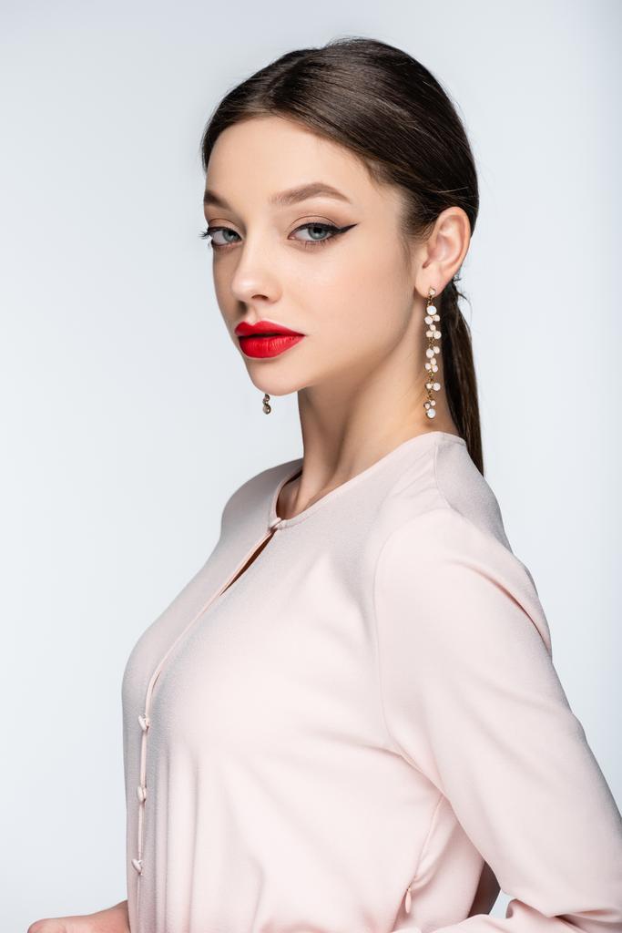pretty woman in earrings and blouse looking at camera while posing isolated on grey - Photo, Image