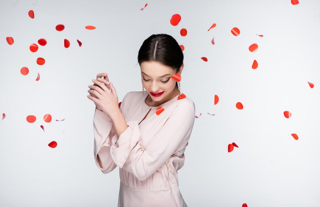 young and happy woman near falling rose petals on grey - Foto, Bild