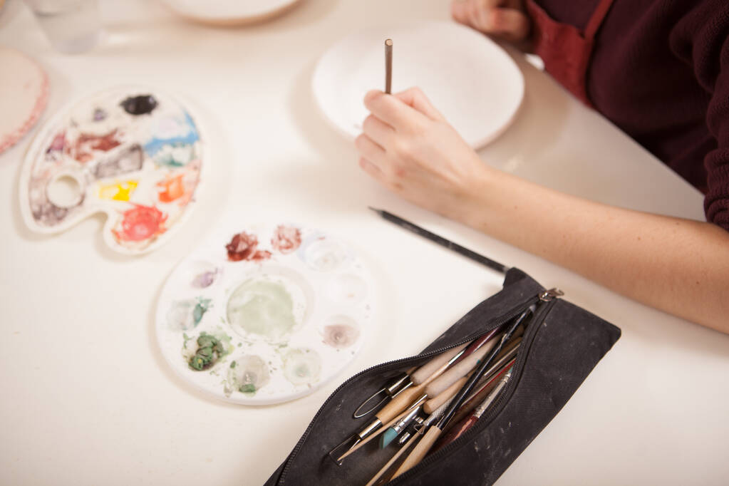 Artista donna irriconoscibile che dipinge su un piatto di ceramica, decorando stoviglie - Foto, immagini