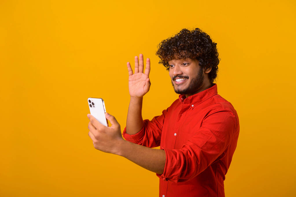Pozitivní vousatý muž se usmívá, dělá selfie na kameře smartphonu, blogger komunikuje, nahrává video pro následovníky v sociálních sítích. Vnitřní studio pořízené izolovaně - Fotografie, Obrázek