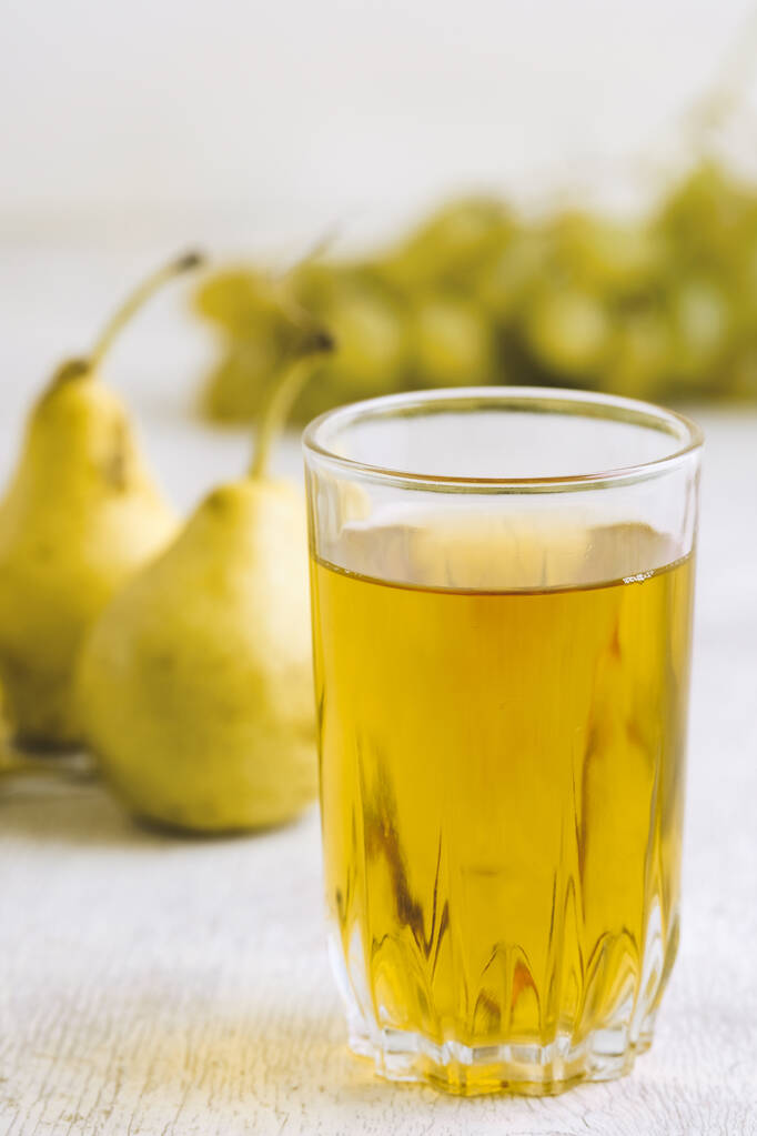 sap van peren en druiven in een glas op een witte houten ondergrond - Foto, afbeelding