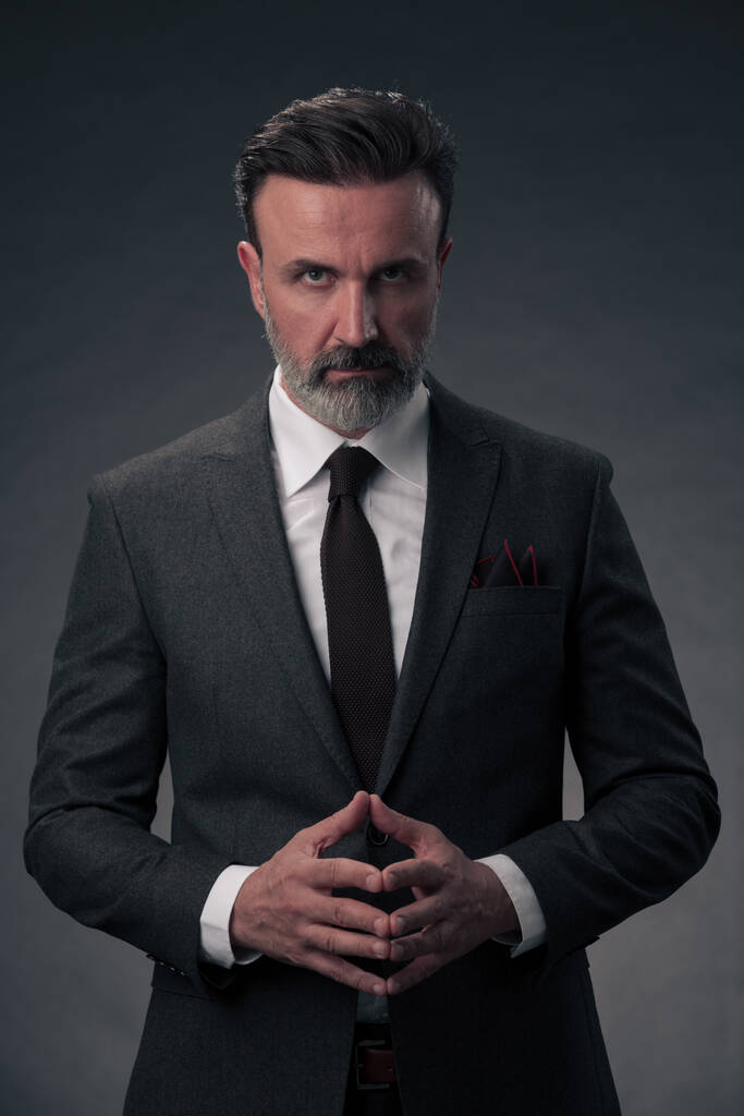 Porträt eines eleganten Geschäftsmannes mit Bart und lässiger Businesskleidung in einem Fotostudio, isoliert auf dunklem Hintergrund und gestikulierend mit den Händen. Hochwertiges Foto - Foto, Bild