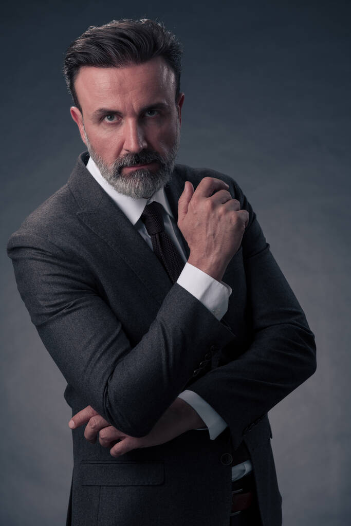 Porträt eines eleganten Geschäftsmannes mit Bart und lässiger Businesskleidung in einem Fotostudio, isoliert auf dunklem Hintergrund und gestikulierend mit den Händen. Hochwertiges Foto - Foto, Bild