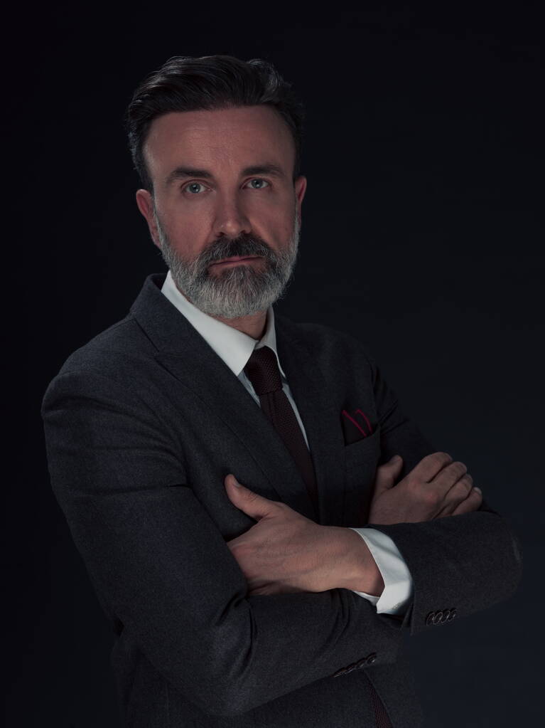 Retrato de um elegante homem de negócios sênior elegante com barba e roupas de negócios casuais em estúdio de fotografia isolado em fundo escuro gesticulando com as mãos. Foto de alta qualidade - Foto, Imagem