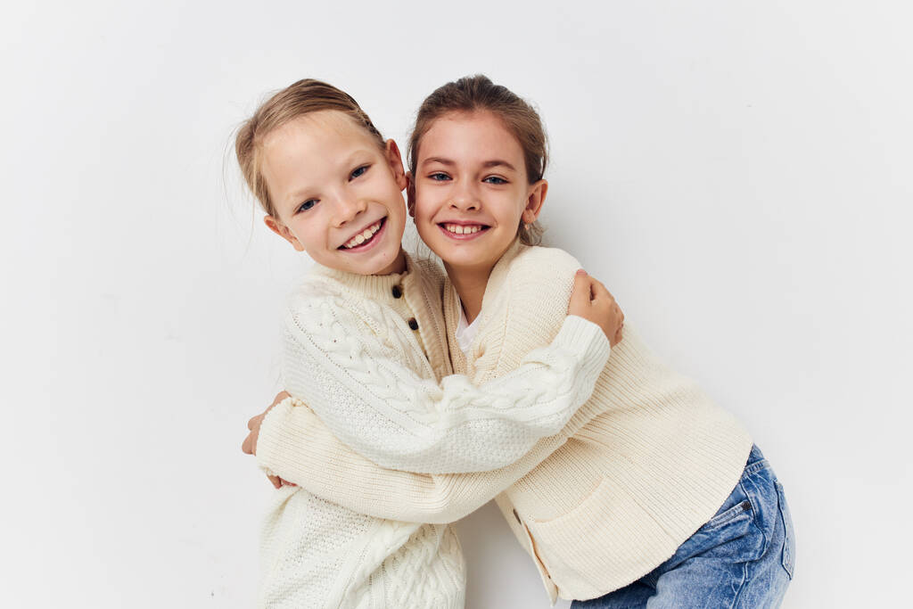 two little girls in sweaters posing childhood light background - Photo, Image