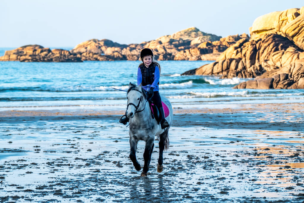 BURTONPORT, PAŃSTWO DONEGALNE, IRLANDIA - GRUDZIEŃ 18 2021: Rodzina wychowanków jeździ konno po plaży - Zdjęcie, obraz