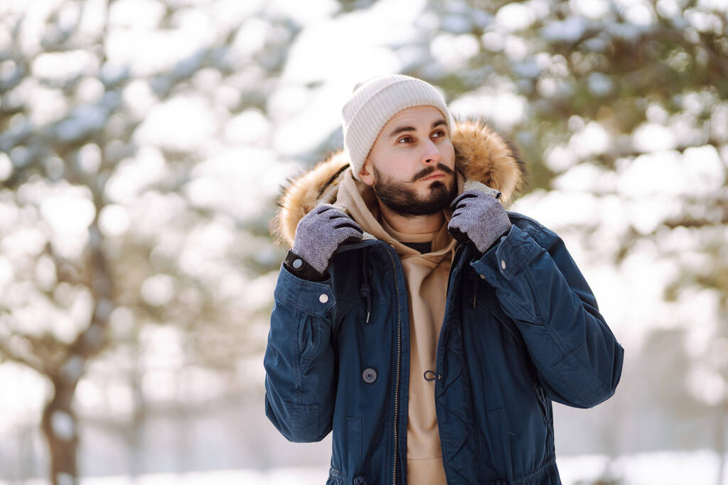 Handsome bearded young  man standing outdoors fur hood in winter season forest. Season holiday leisure. Nature. - Photo, image