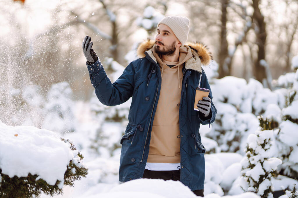 Handsome bearded young  man standing outdoors fur hood in winter season forest. Season holiday leisure. Nature. - Фото, изображение