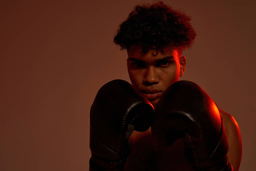 Selbstbewusster Boxer mit Boxhandschuhen blickt in die Kamera - Foto, Bild