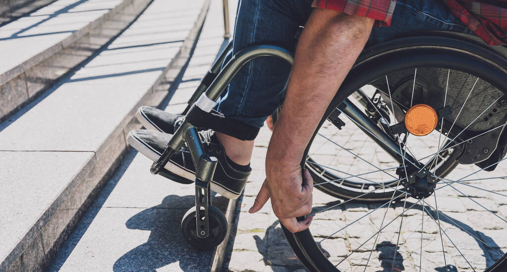 Jongeman met een lichamelijke beperking die rolstoel gebruikt voor de trap - Foto, afbeelding
