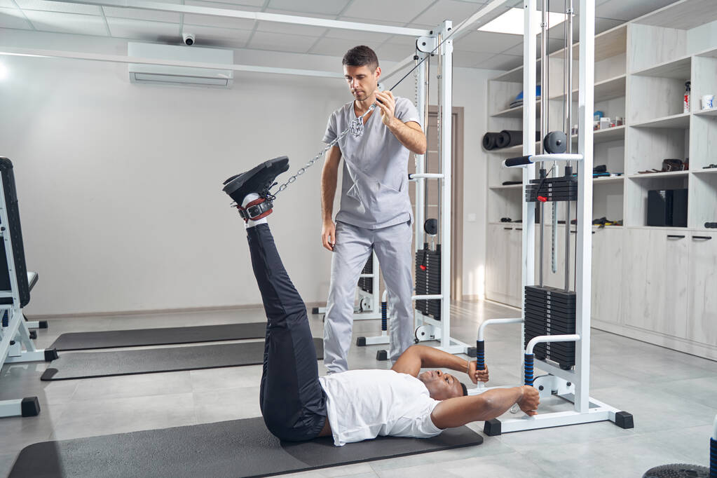 Man doing stretching exercise using gym equipment - Photo, image