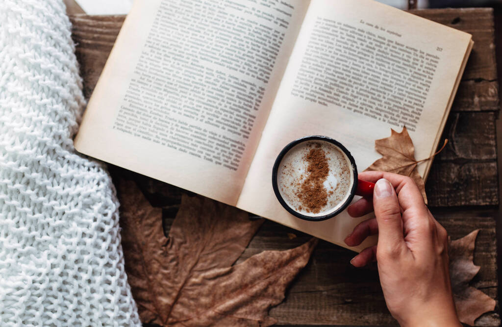рука жінки, що тримає чашку кави, читаючи книгу восени
 - Фото, зображення