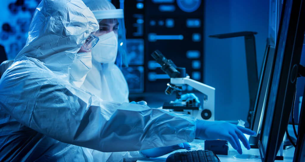 Los científicos trabajan en un laboratorio científico moderno utilizando equipos de laboratorio, microscopio y tecnología informática. Invención de nuevas vacunas. Concepto de Ciencia y Salud. - Foto, imagen
