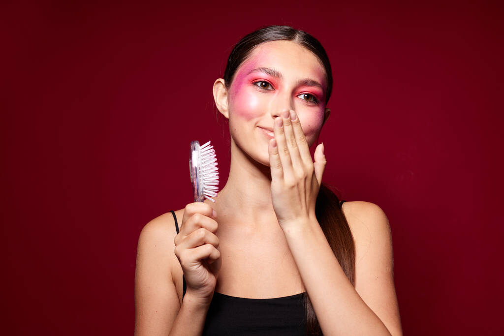 Portrait of beautiful young woman pink face makeup posing attractive look with a comb close-up unaltered - Photo, Image