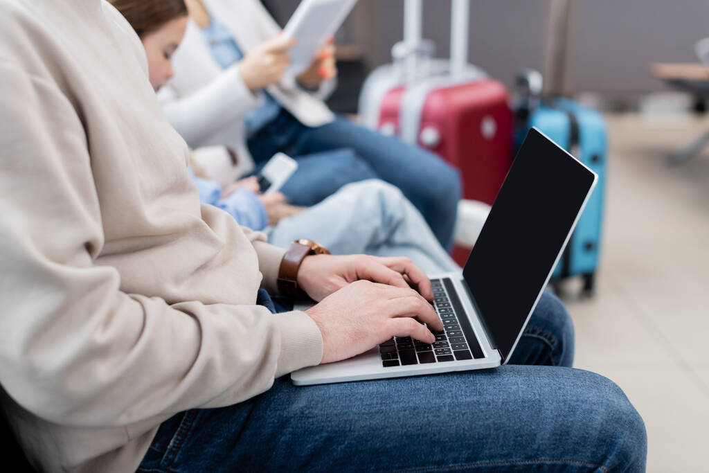 homme utilisant un ordinateur portable près de la famille floue à l'aéroport  - Photo, image