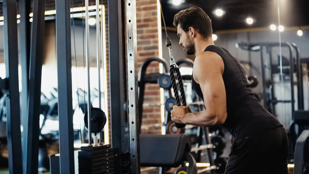 bearded sportsman exercising on fitness machine in sports center  - Foto, Imagem