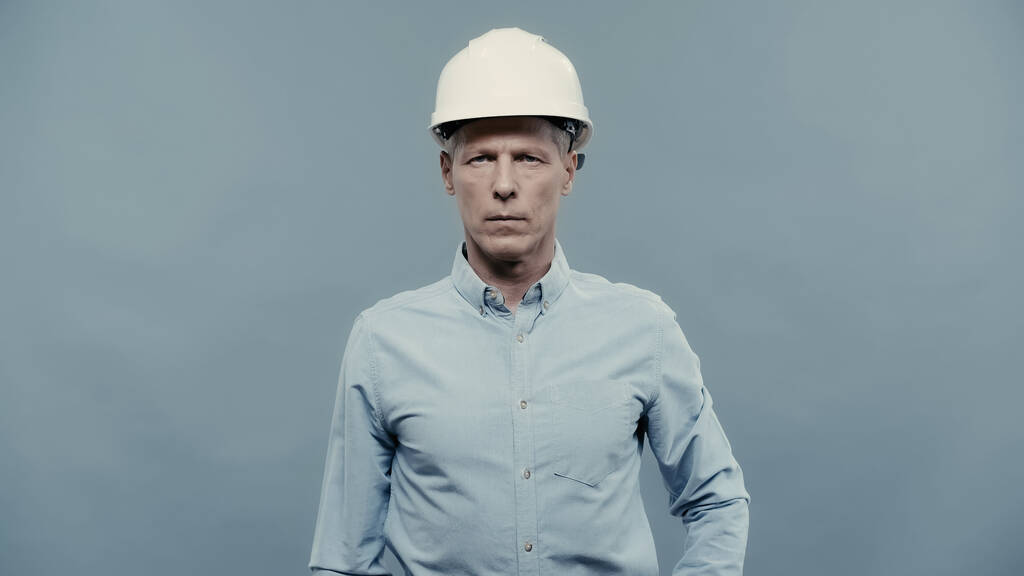 Mature engineer in protective helmet looking at camera isolated on grey  - Foto, immagini