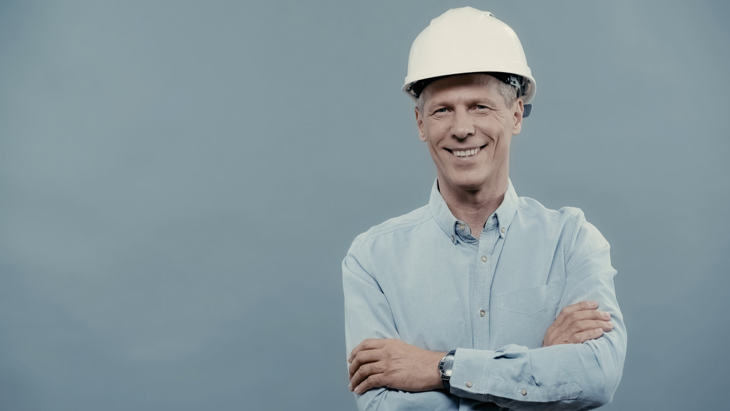 Positive engineer in hardhat crossing arms isolated on grey  - Foto, Imagem
