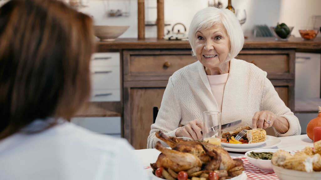 senior woman smiling during thanksgiving dinner with blurred guest - Foto, Bild